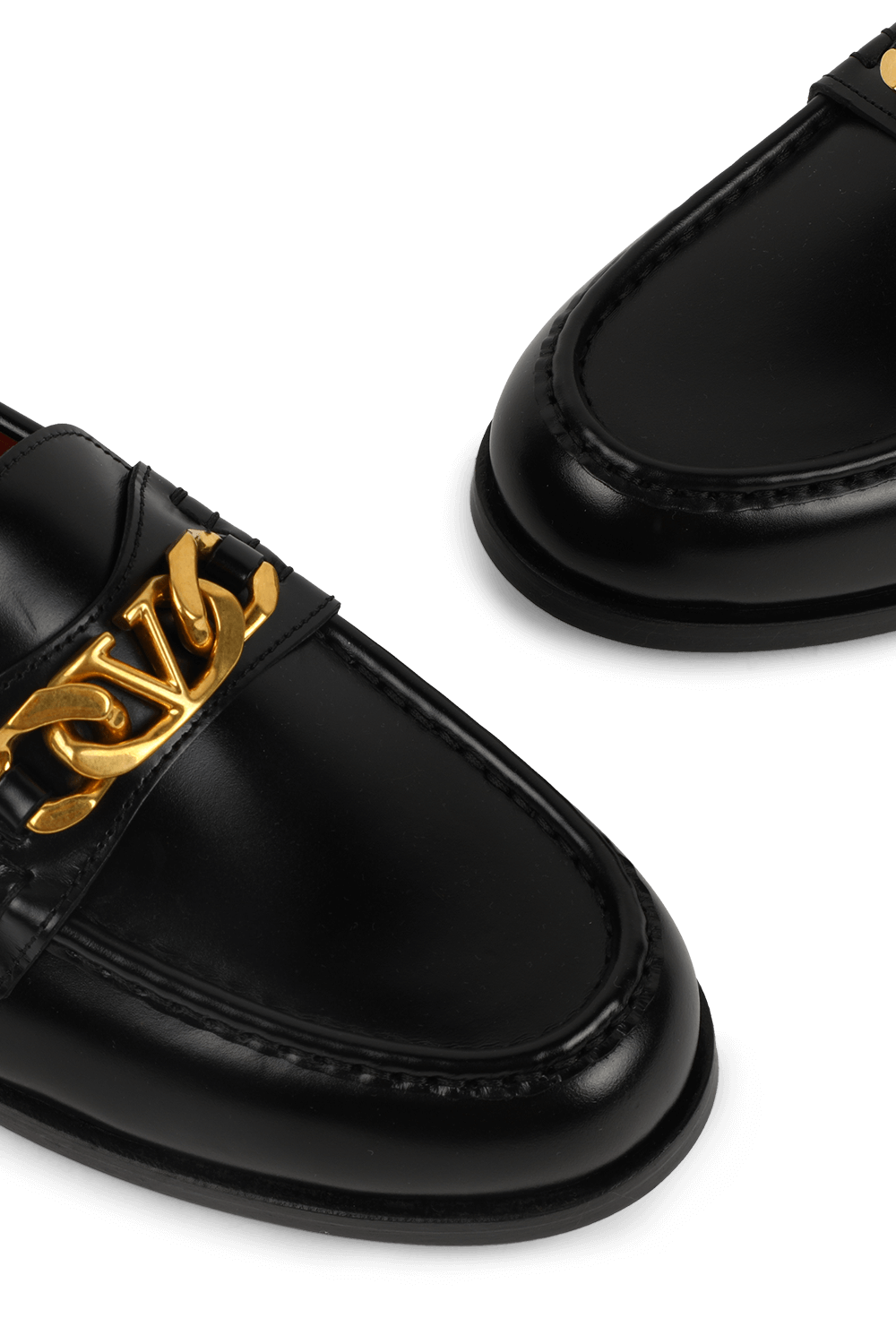 תמונת תקריב של נעלי מוקסין מעור מבריק עם אלמנט זהב