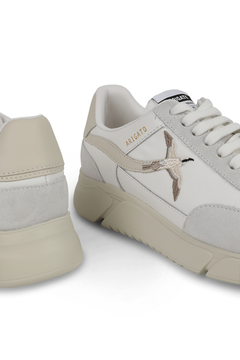 תמונת תקריב של נעלי סניקרס ג'נסיס לבנות עם סמל רקום