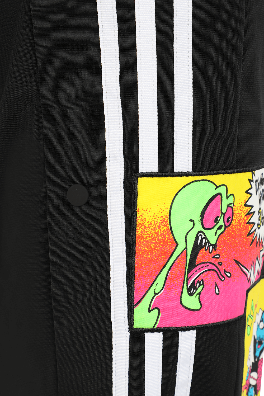 תמונת תקריב של ג'רמי סקוט לאדידס מכנסי ג'וג עם פאצ'ים צבעוניים בצבע שחור