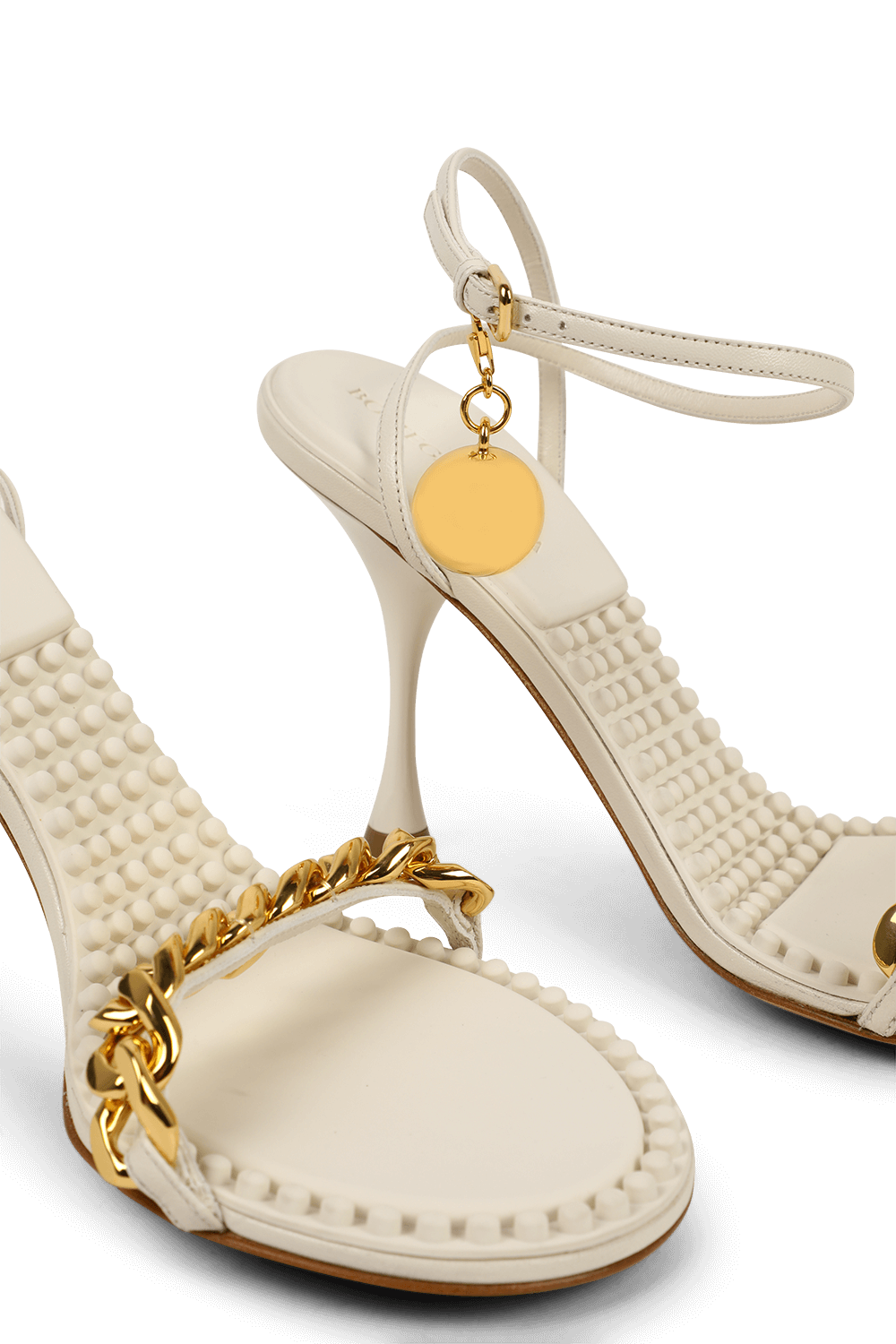 תמונת תקריב של סנדלי עקב לבנים עם שרשרת זהב