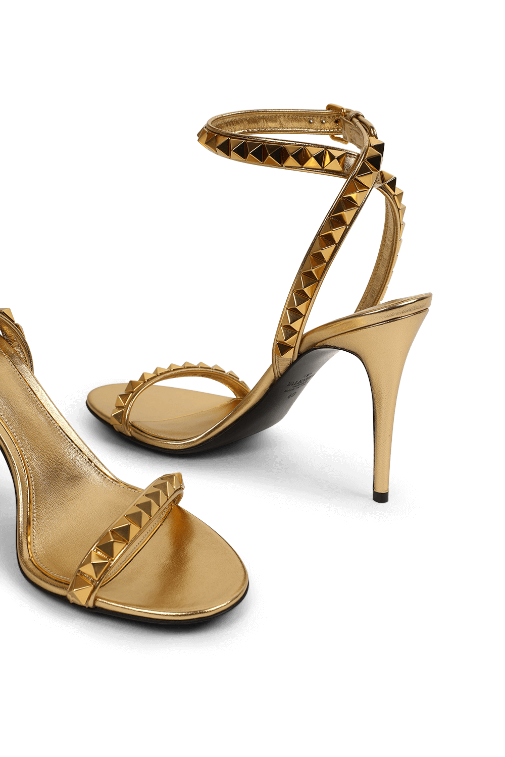 תמונת תקריב של נעלי עקב מוזהבים בעיטור ניטים