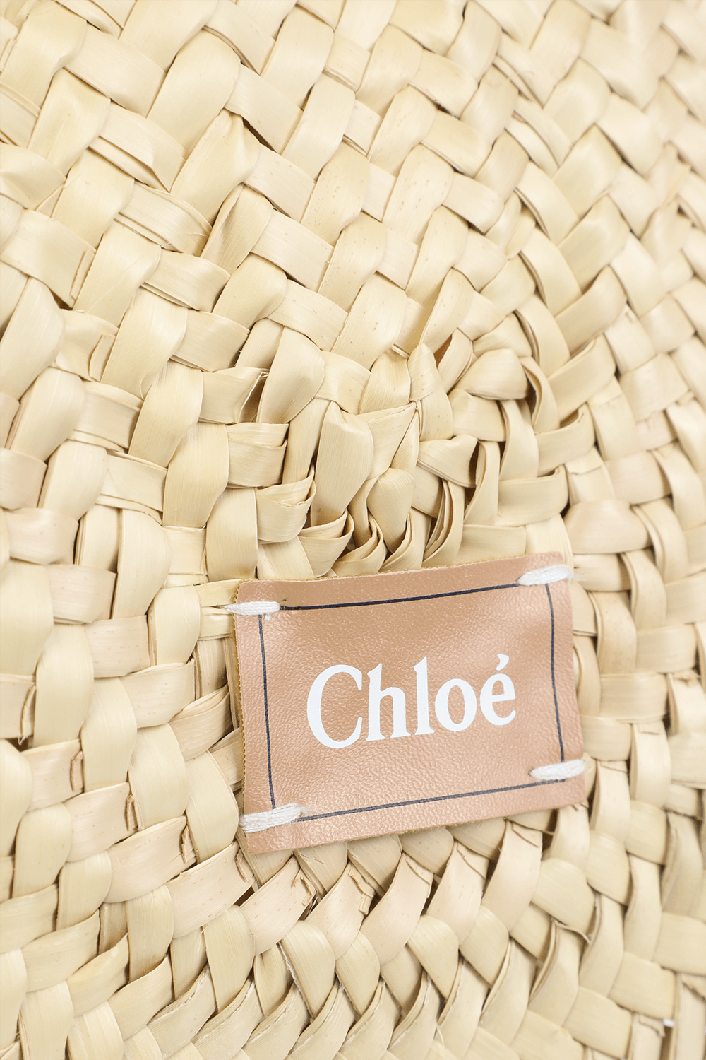 תמונת תקריב של תיק קש עם פפיון לבן