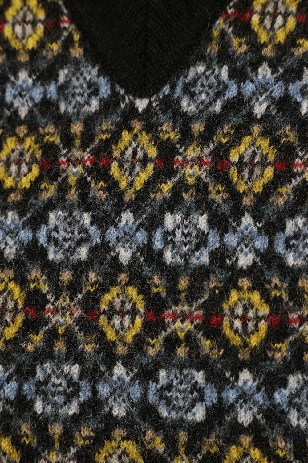 תמונה אחורית של אפודת צמר בדוגמה ייחודית בגווני שחור כחול וצהוב