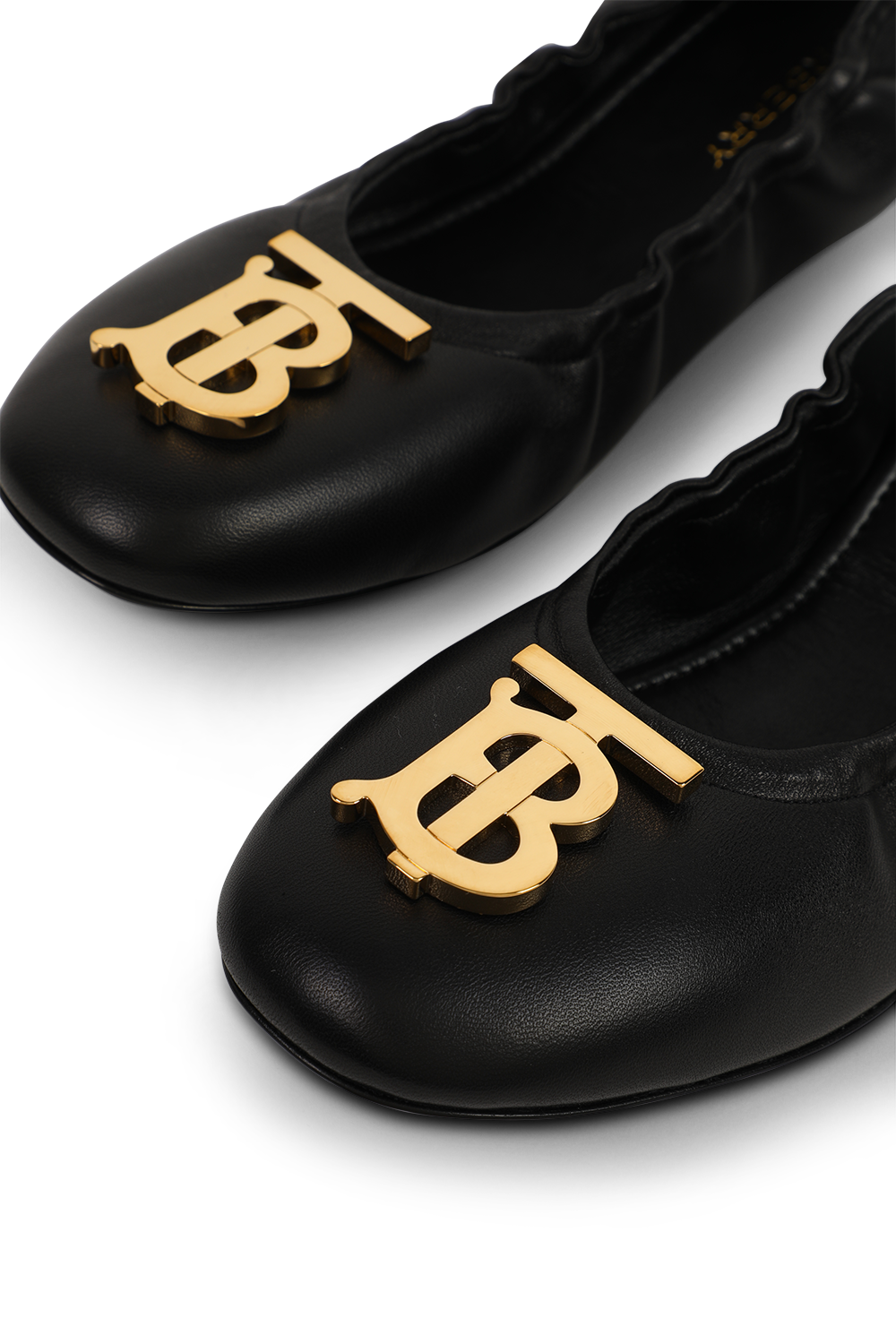 תמונת תקריב של נעלי בלרינה שחורות מעור עם אלמנט מוזהב