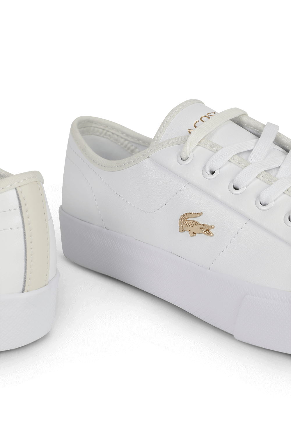 תמונת תקריב של נעלי סניקרס לבנות עם לוגו תנין מוזהב
