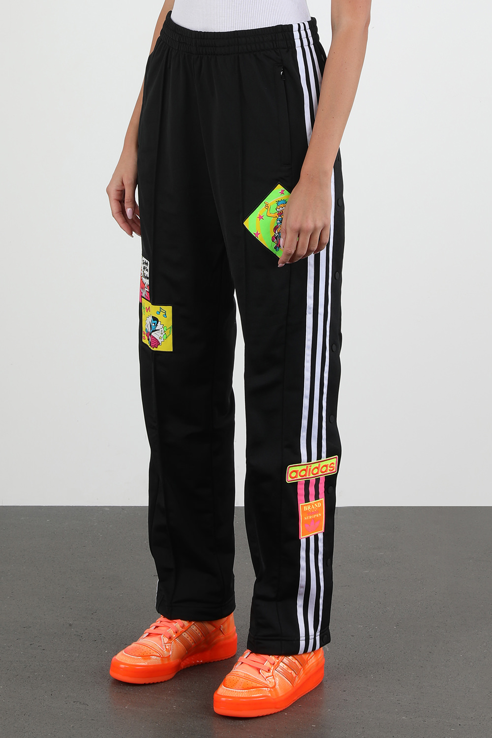 תמונת דוגמן קידמית של ג'רמי סקוט לאדידס מכנסי ג'וג עם פאצ'ים צבעוניים בצבע שחור