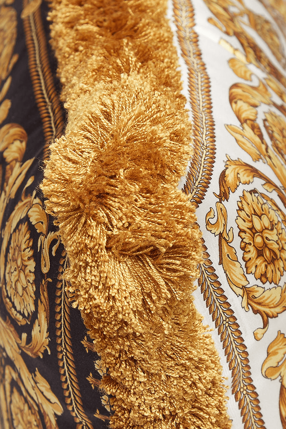 תמונת תקריב של כרית לבנה עם פרנזים והדפס בארוק זהוב